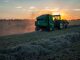 Un tracteur dans un champ, au coucher de soleil