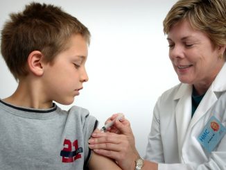 Une enfant se faisant vacciner par une infirmière.